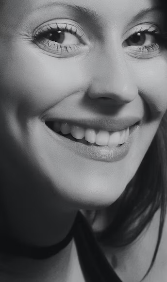 black and white photo of a woman smiling with perfectly aligned teeth