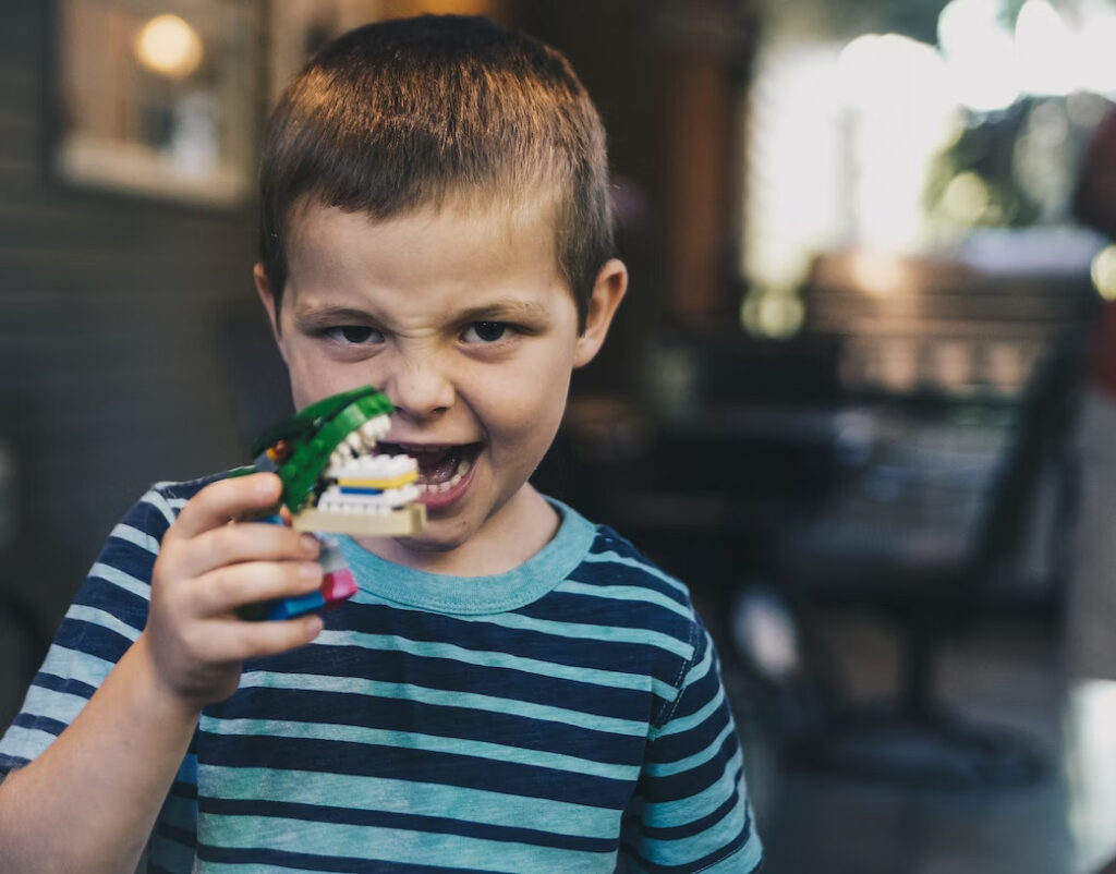 a little boy holding a dental model while looking at the camera